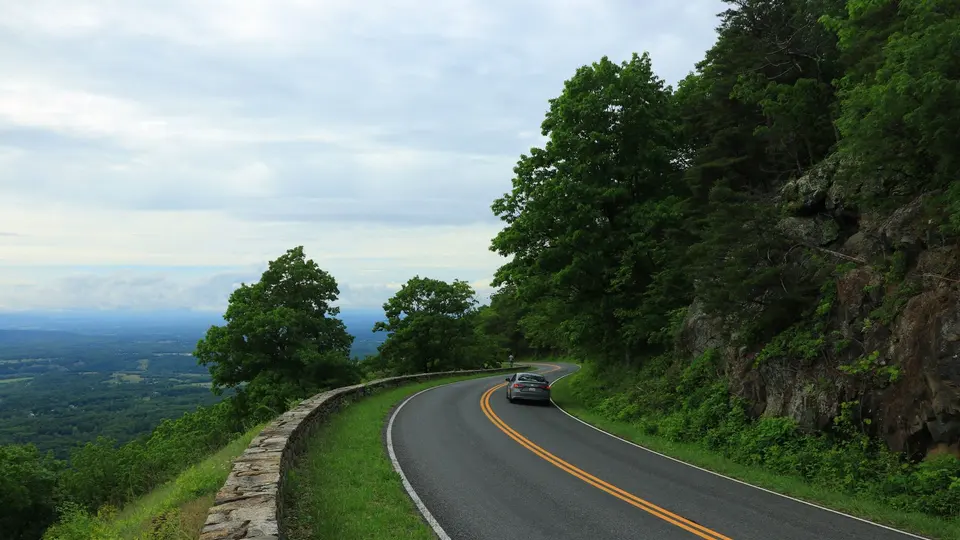 A curving mountain road in Virginia surrounded by green trees