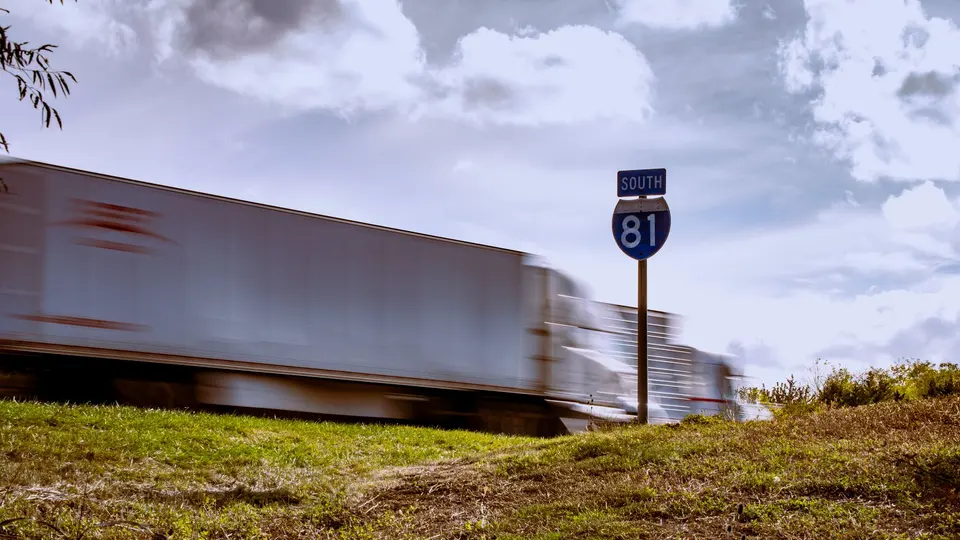A tractor-trailer in motion past an Interstate 81 South sign