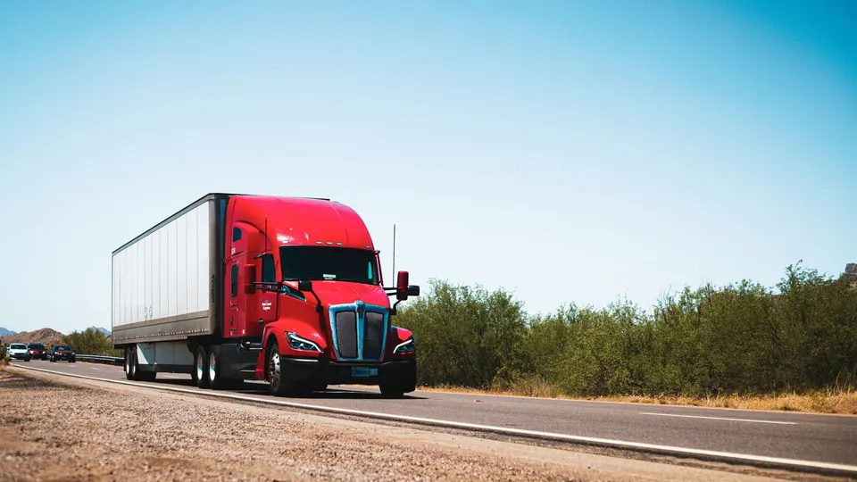 A red tractor-trailer driving along a U.S. highway