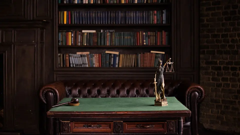 A law library with a statue of Lady Justice and a gavel on a desk